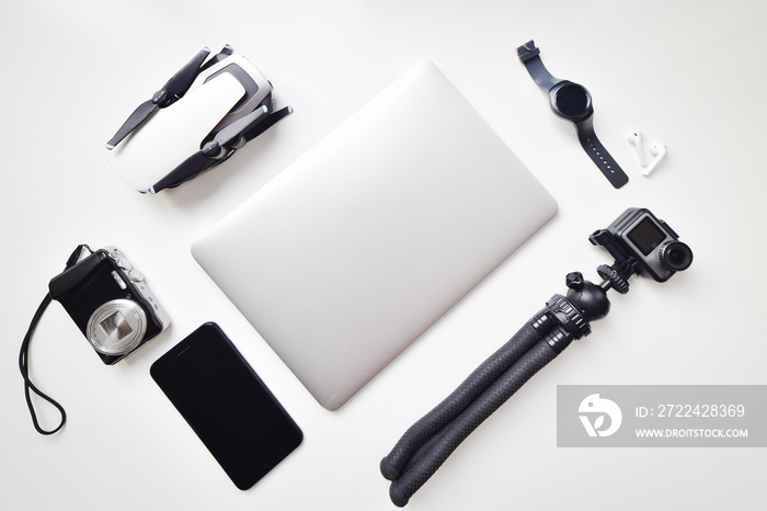 Flat lay daily vlogging lightweight gadget travel set up isolated on white table background: compact camera, phone, watch, compact camera, drone, notebook, earphones