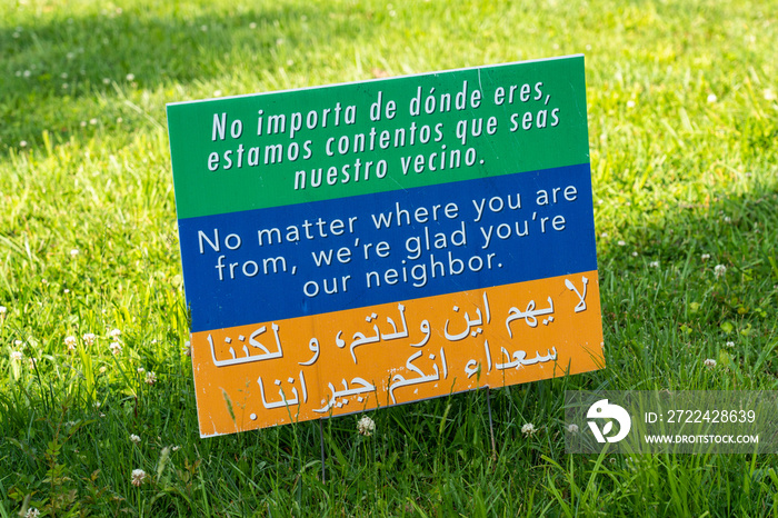 This sign on a lawn welcomes people to the neighborhood in 3 languages, spanish, english and arabic and is creative commons so many people will print it and welcome all to their community.