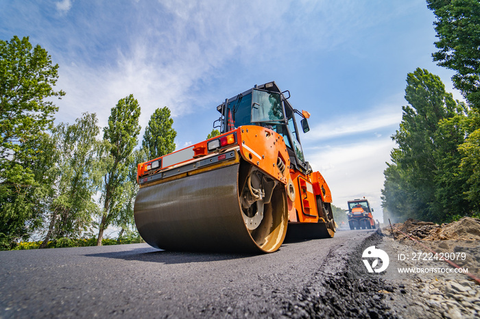 Road repair, compactor lays asphalt. Heavy special machines. Asphalt paver in operation. Side view. Closeup.