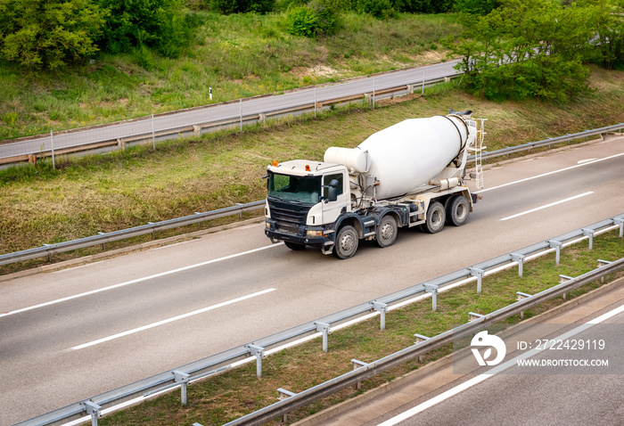 White concrete mixer or cement mixer truck driving along the highway