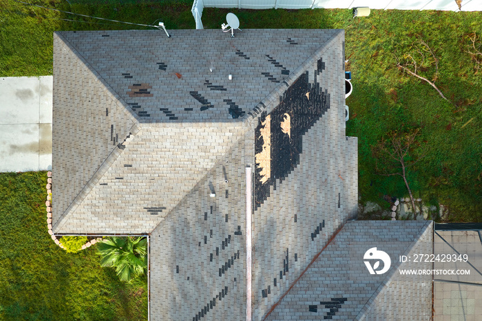 Damaged house roof with missing shingles after hurricane Ian in Florida. Consequences of natural disaster