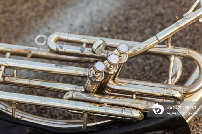 close up of the keys of a sousaphone resting on the ground during a marching band rehearsal