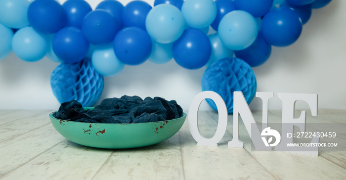 sliver, blue and white decoration for a 1st birthday cake smash studio photo shoot with balloons, paper decor, cake and topper. High quality photo