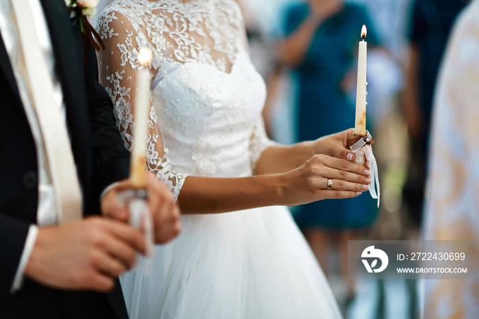 happy bride and stylish groom holding candles wedding ceremony, wedding couple at matrimony in church, emotional moment, religion unity concept