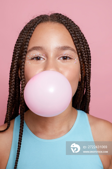 Studio portrait of girl blowing bubble gum