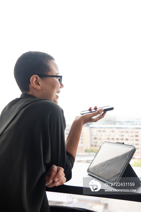 Woman using digital tablet and phone in office