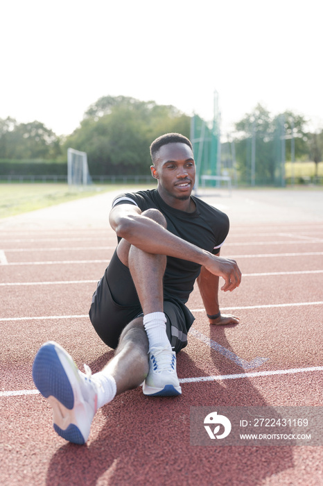 Athlete stretching legs before training at sports track