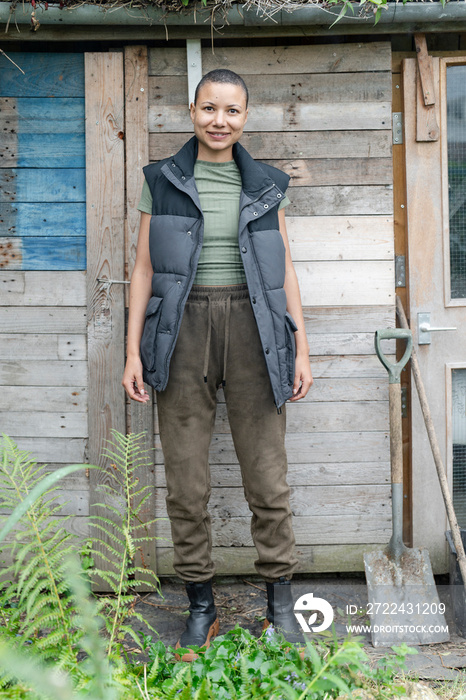 Portrait of smiling woman standing in front of hut in urban garden