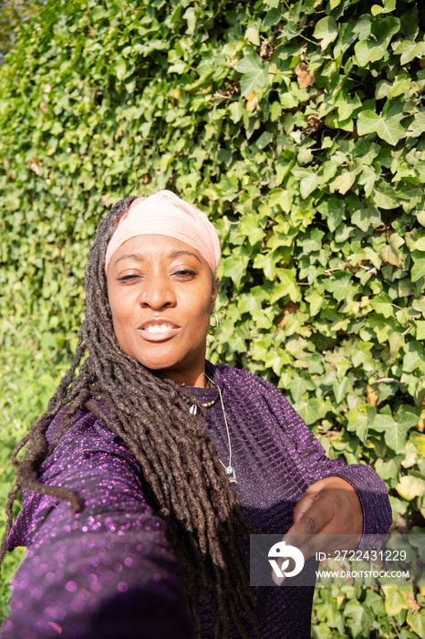 Portrait of beautiful woman with dreadlocks in front of ivy wall