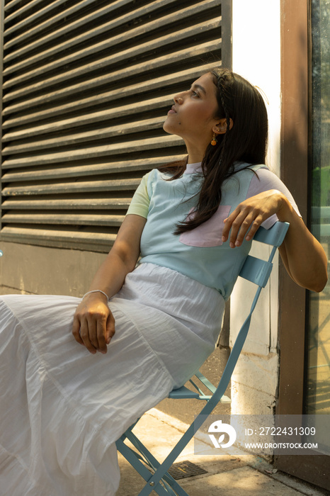 Young woman sitting in sidewalk cafe