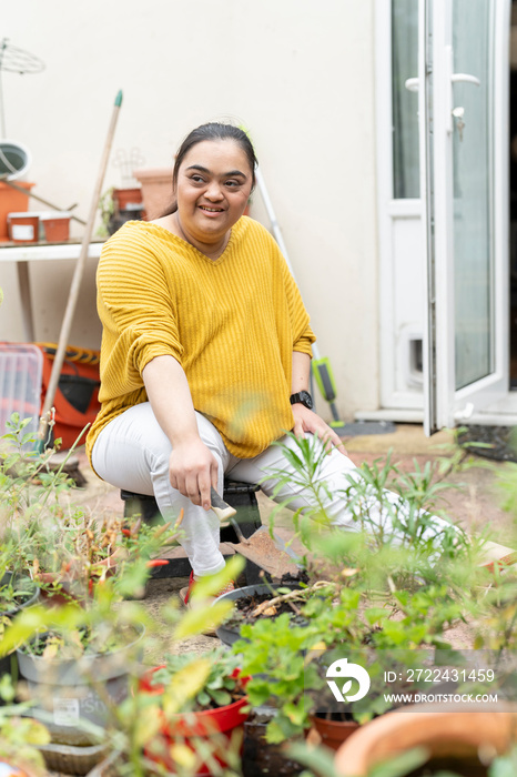 Young woman with down syndrome planting flowers in garden