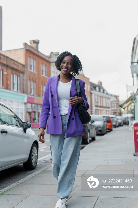 Smiling woman in purple jacket walking in city