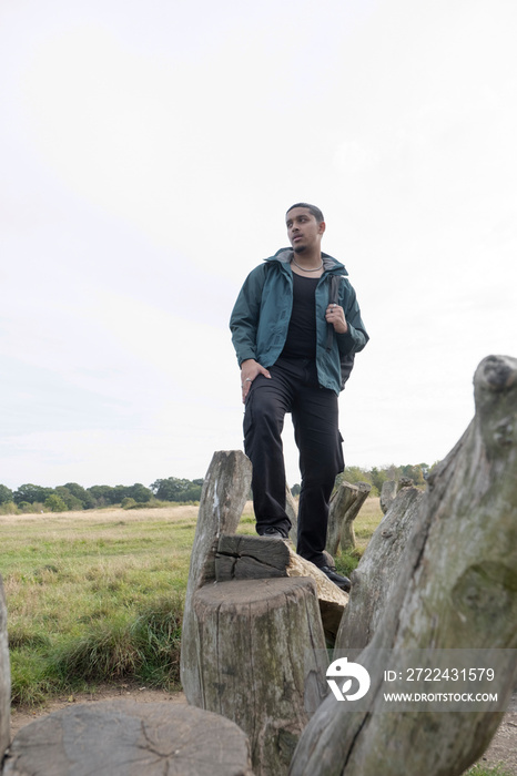 Portrait of man with backpack standing on old wooden posts