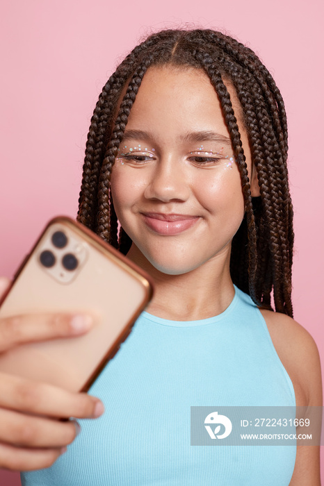 Studio shot of smiling girl with braids holding smart phone