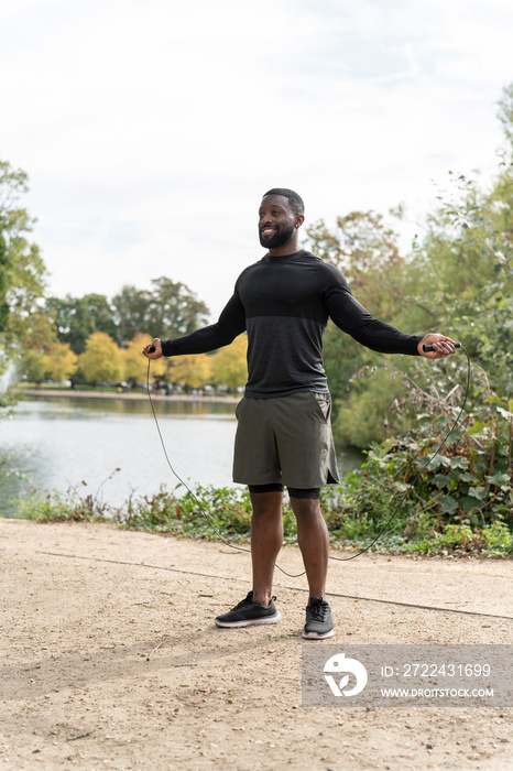 Smiling athletic man with jump rope in park