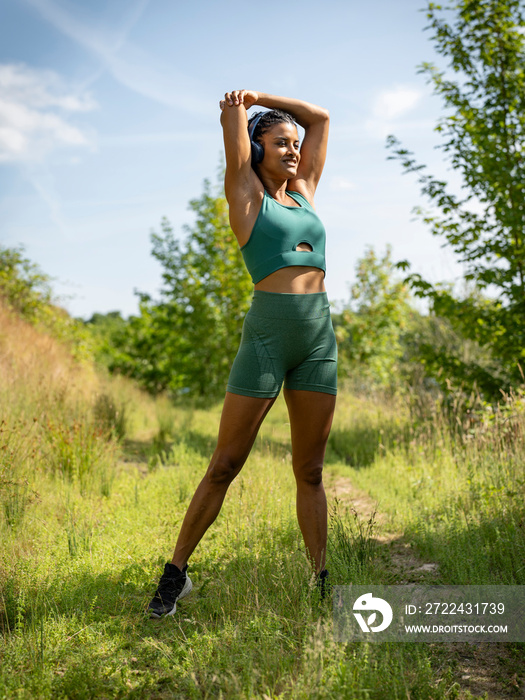 Woman stretching in meadow on sunny day