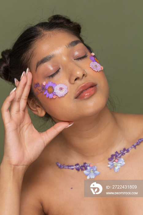 Studio portrait of woman with flowers on face and collarbone