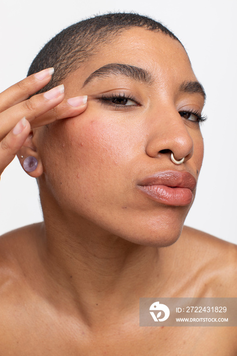 Studio portrait of woman with nose ring touching face