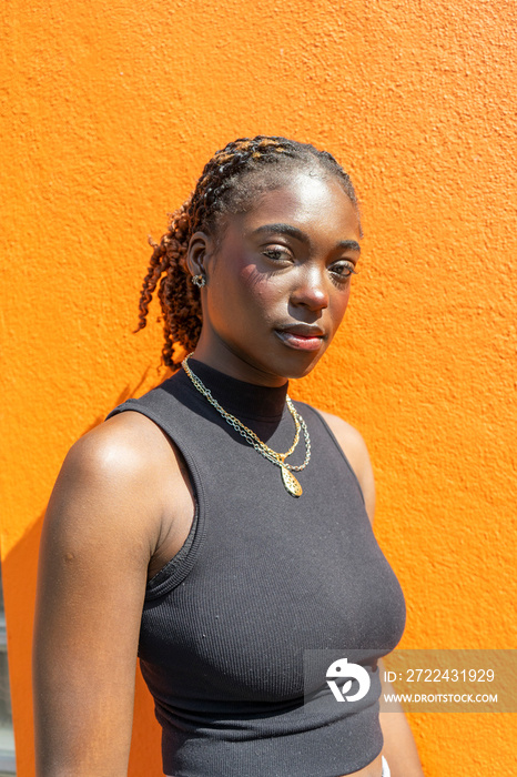 Portrait of young woman standing against red wall