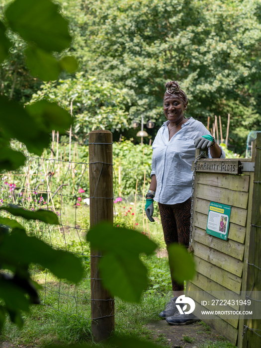 Portrait of smiling mature woman opening gate to allotment