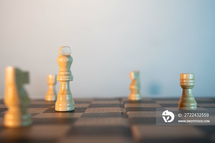 Chess game with pure white pieces. White background behind. Front view of a chess game dominated by the white pieces. Queen, knight and bishop on chessboard.