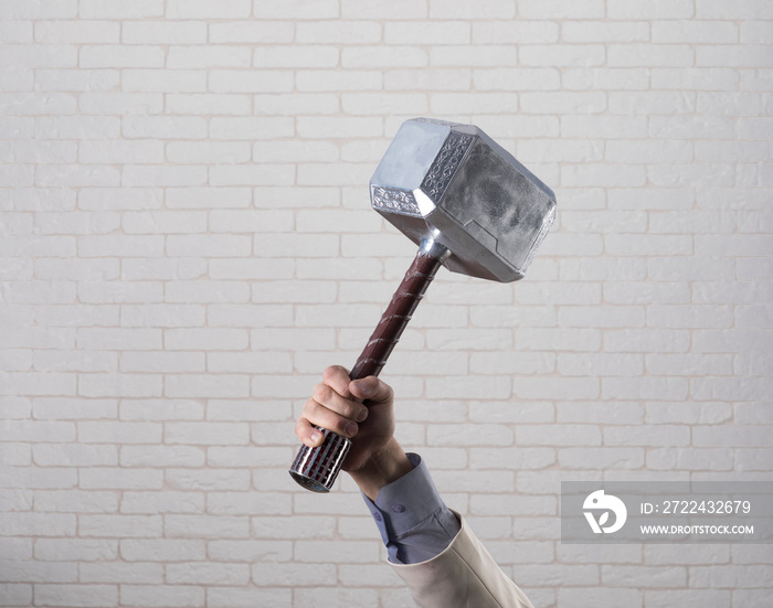 businessman’s hand holds hammer Thor