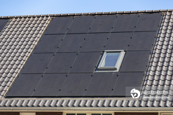 Solar panels on the tiled roofs of new buildings against the blue sky.