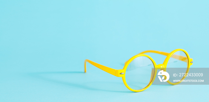 Yellow round glasses on light blue background with copy space