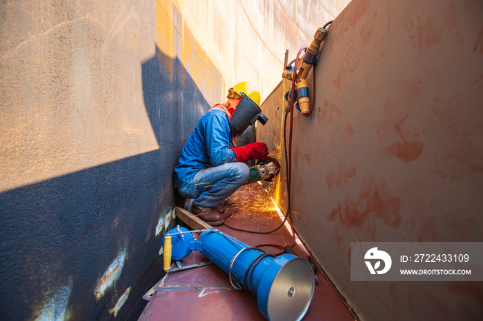 Male worker wearing protective clothing and repair grinding storage tank