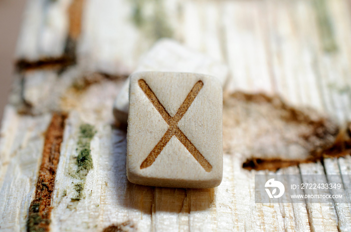 Wooden rune Gebo close-up on a wooden background. Soft focus