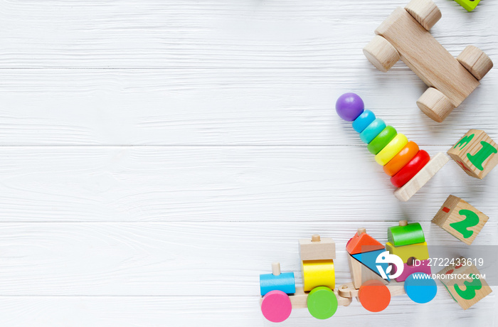 Kids toys: pyramid, wooden blocks, xylophone, train on white wooden background. Top view. Flat lay. Copy space for text