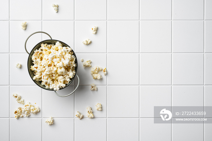 Heap of delicious popcorn on white ceramic squared tile table background, top view flat lay, with copy space for text