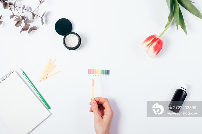 Woman check cosmetics pH level by using litmus paper