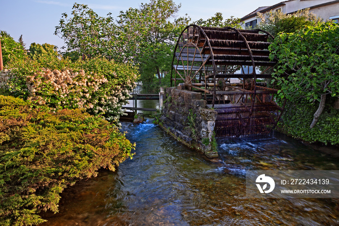 L’Isle-sur-la-Sorgue, Vaucluse,.Avignon, France: view of the canal with the wheel of the old water mill