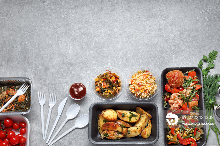 Different containers with delicious food on grey background