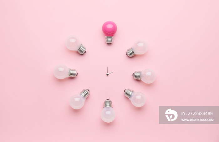 Creative clock made of light bulbs on color background