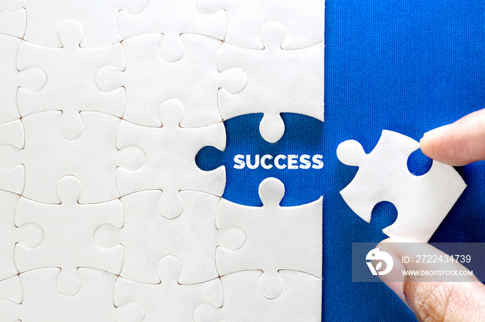 Close up piece of white jigsaw puzzle with SUCCESS text , a concept of business challenge success completion with teamwork