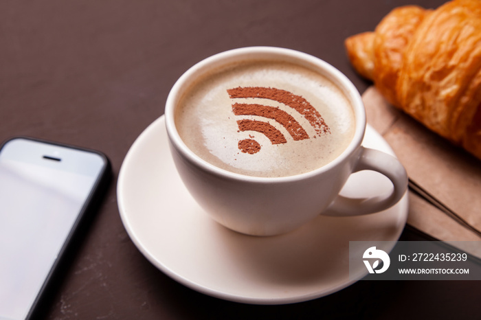 Cup of coffee with WiFi sign on foam. Free access point to the Internet WiFi. I like coffee break with croissant