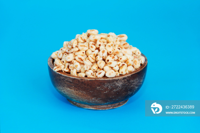 grains of edible puffed rice in a decorative plate on a blue background