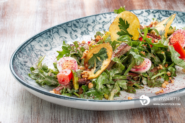 Duck breast salad with potato chips and fresh vegetables. On a decorative plate