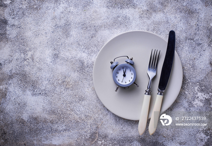 Grey alarm clock in empty plate.