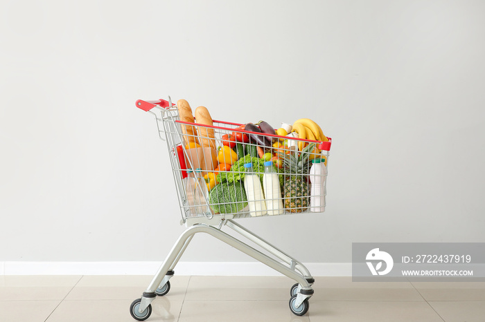 Shopping cart with products near light wall