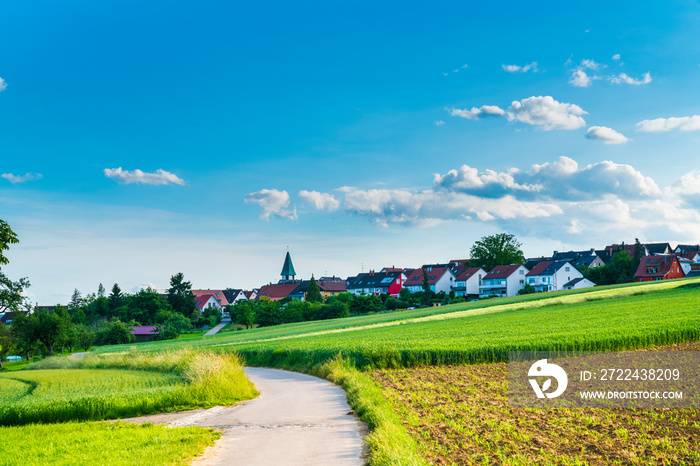 Germany, City ostfildern kemnat houses and church of  behind curved road and green fields in summer a beautiful nature landscape view with sun