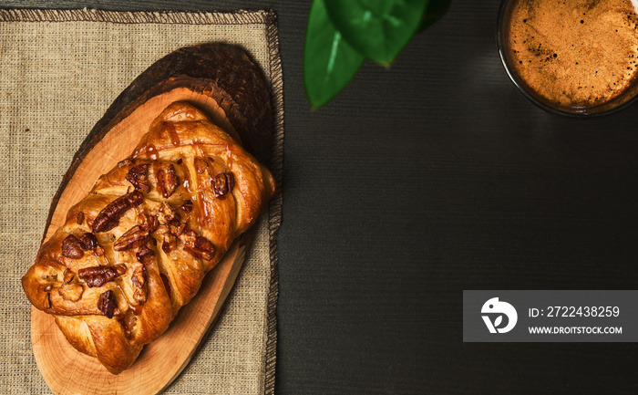 Espresso coffee braided with pecans and maple syrup on a dark table. Sweet pastries for breakfast at the hotel. View from above