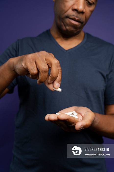 Man taking medicine against purple background