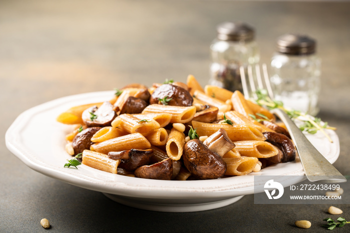 Fancy organic whole grain penne pasta with champignons, pine nuts and thyme. Healthy italian food concept.