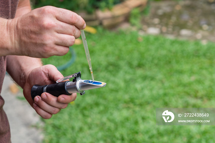 Young man holding refractometer for measure craft beer sugar level