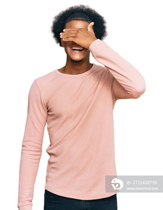 African american man with afro hair wearing casual clothes smiling and laughing with hand on face covering eyes for surprise. blind concept.