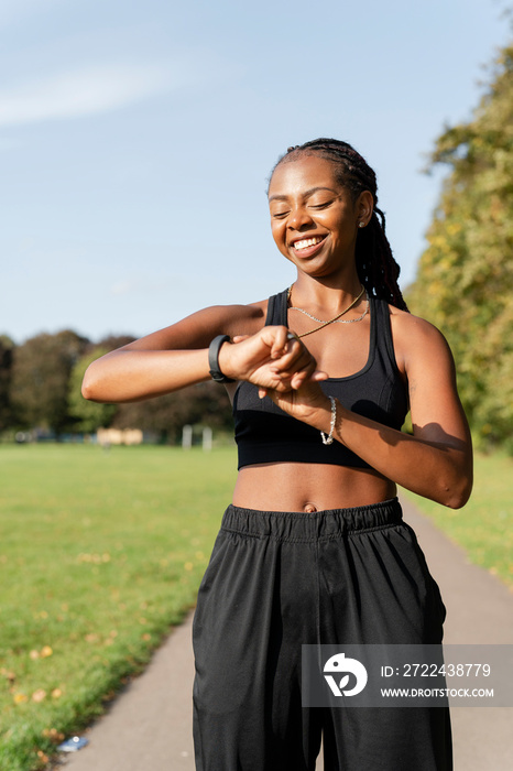 Smiling young woman checking time after jogging