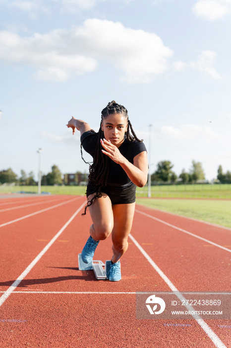 Female athlete sprinting off starting line at stadium